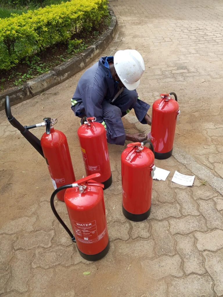 Lindum Systems technician inspecting a fire extinguisher during routine maintenance service in Kenya